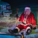 A dirty, beat-up Santa sits on the ground looking defeated